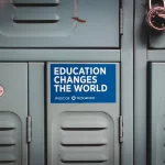 Gray school locker with a blue sticker on it that reads education changes the world. It shows why college degree is important