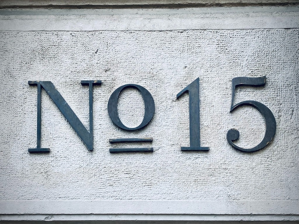 Gray wall with the number 15 on it so show that a student needs fifteen credits a semester to graduate college on time 