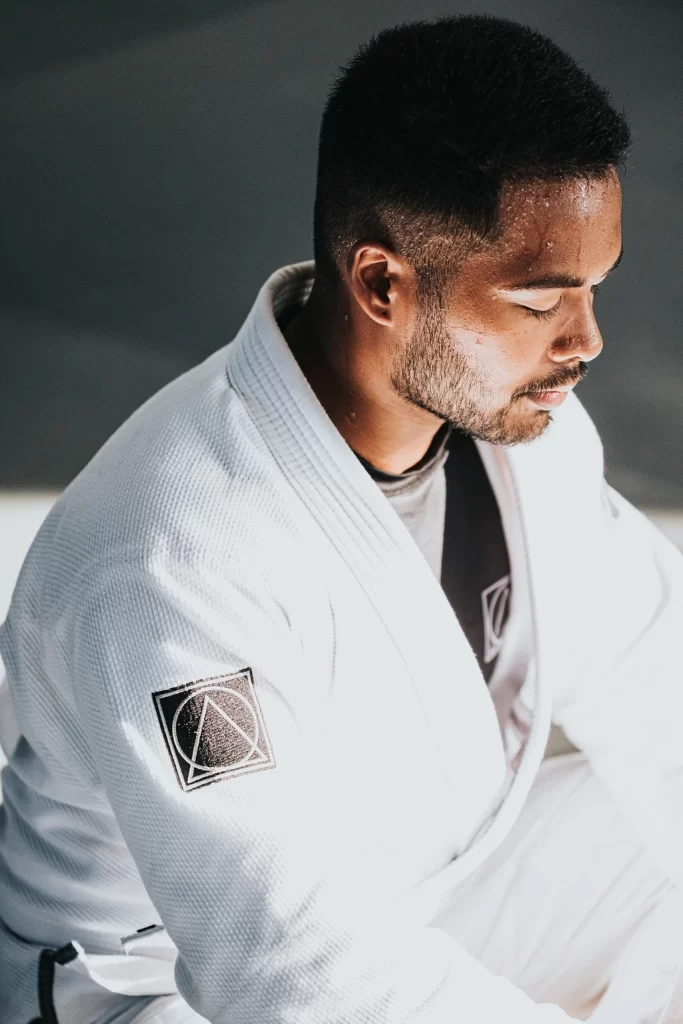 A man sitting in a white karate gi, forehead is dripping with sweat, his eyes are closed as he focuses. It will take determination when you fail a class