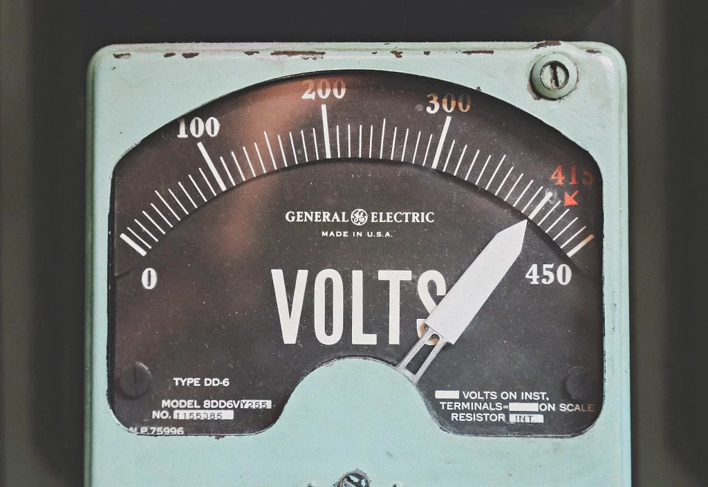 A old and worn general electric volts meter with a white arrow spiking to full volts. This represent taking 15 credits each college semester