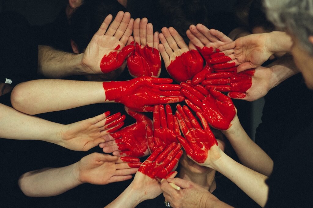 volunteering hands formed together to make a heart with red paint. Being a volunteer is a great Extracurricular Activities for college.