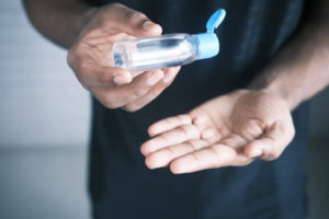 close up of hands holding a bottle of hand sanitizer. Killing germs is how to avoid getting sick
