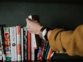 college student reaching for a book on a bookshelf