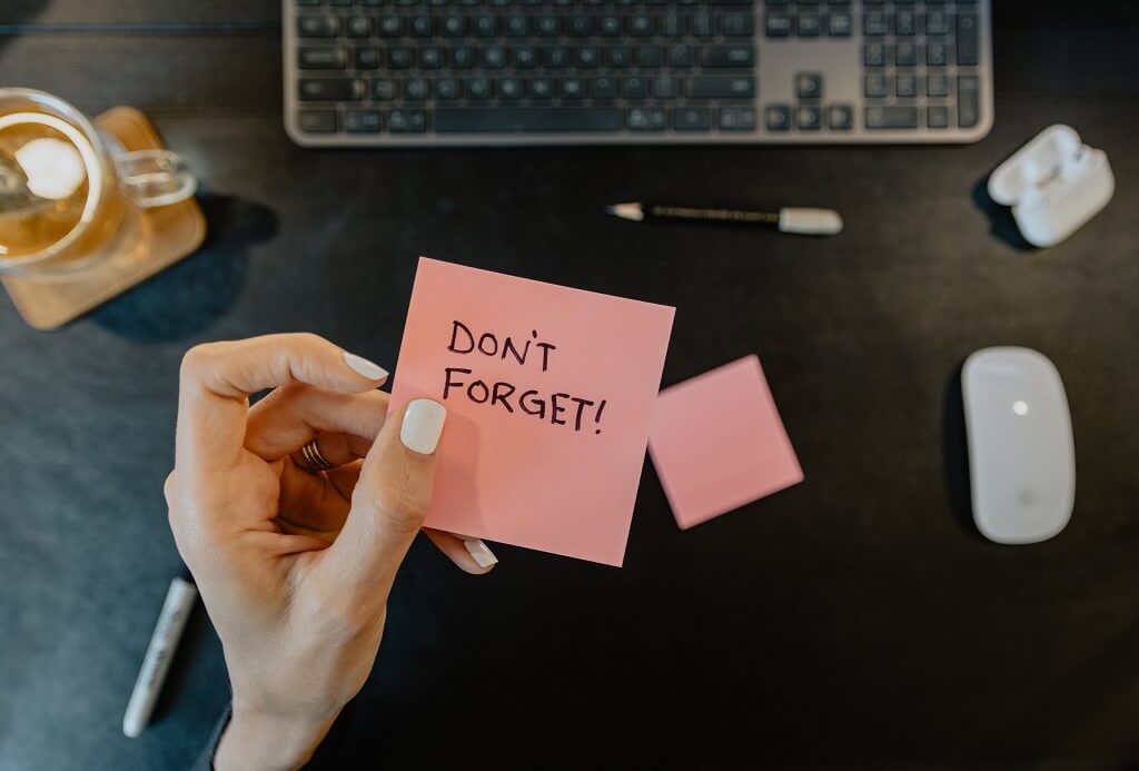 Hand holding Sticky note reminder "Don't forget". A reminder one how to get scholarships for college