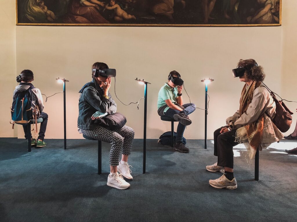 Four people sitting in a room with virtual reality headset on.