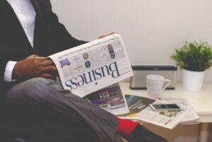 man in a suit sitting reading a business newspaper