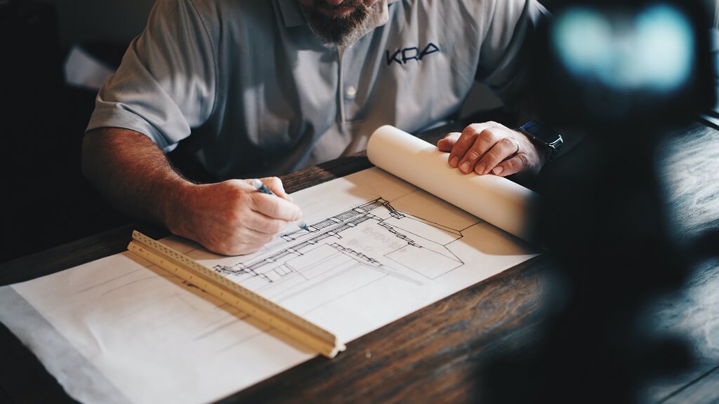 Male architect working at a table uses his math degree to draw house plans