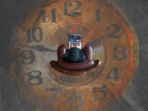 person sitting in a chair with a laptop on their lap. There is a picture of a clock surrounding the chair representing time waster websites