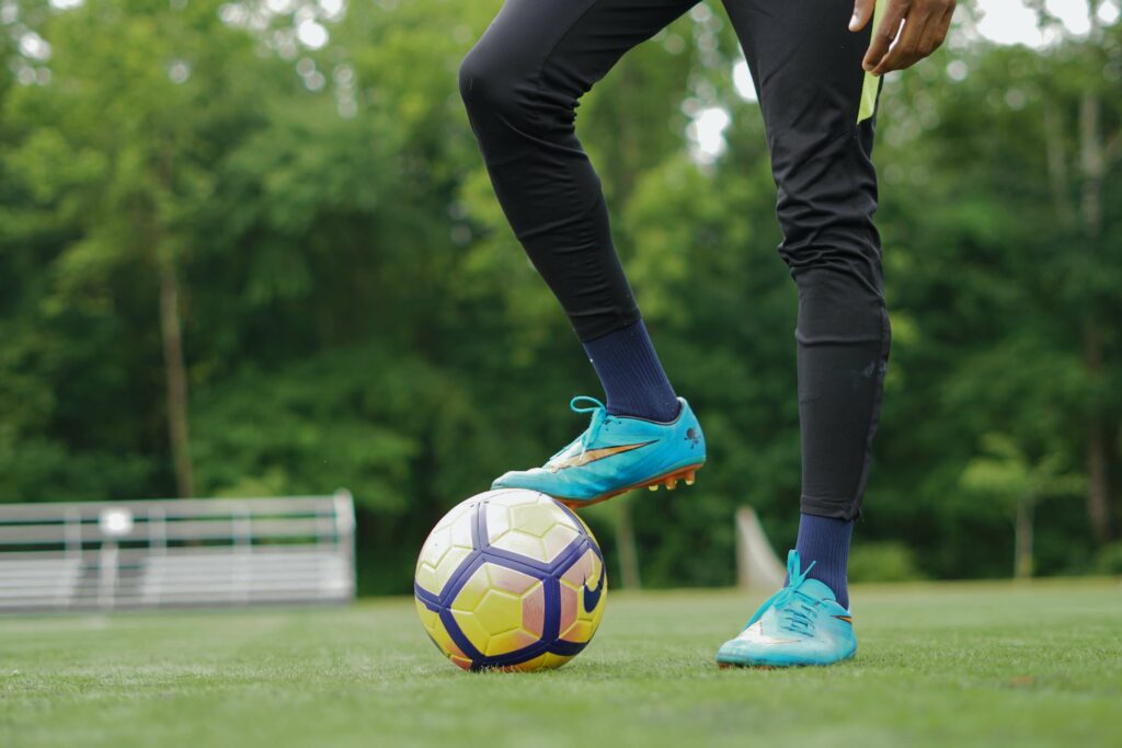 a person in blue nike shoes one foot on a soccer ball