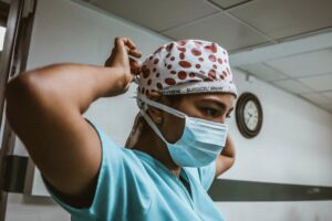 a female nurse in scrubs putting on a mask