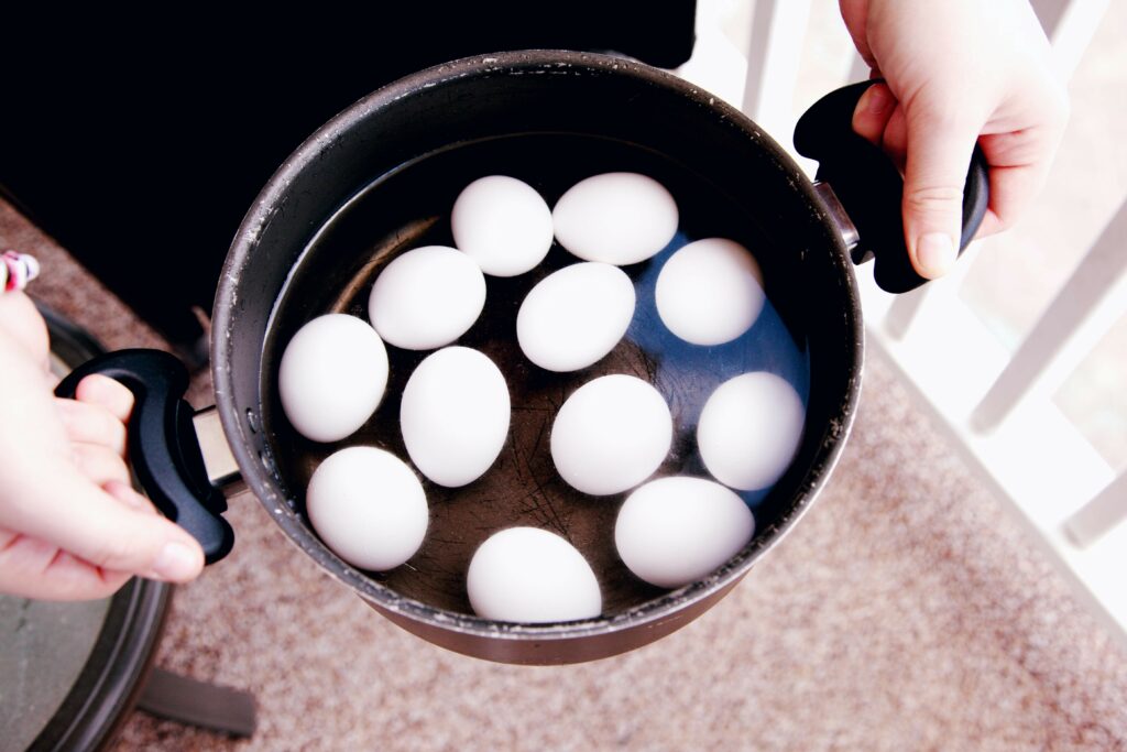 Hands holding a pot with hard boiled eggs inside to meal prep